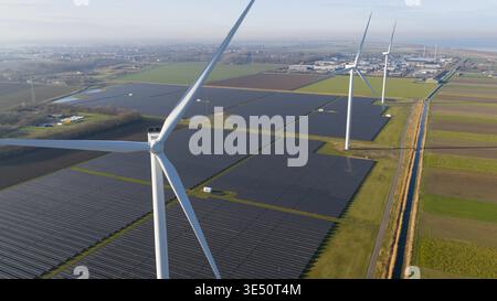Aerial view of a large solar panel array and wind turbines generating renewable energy in a rural landscape. Stock Photo