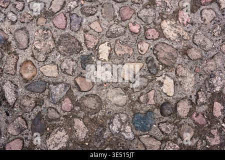 Top view of an old cobblestone pavement made of natural round stones, traditional stone road texture, rustic weathered rock background Stock Photo