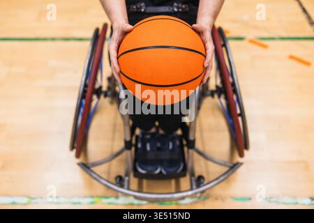 Athlete holding basketball while sitting in wheelchair Stock Photo