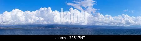 Cloudscape texture 20k panorama of fluffy white clouds over calm blue sea. Wide 4:1 background of dramatic cumulus sky and Mediterranean coastline mou Stock Photo