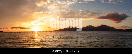 Corsica sunset 15k panorama over calm orange sea with mountain reflections. Scenic Mediterranean view of golden hour and silhouettes of mountains in F Stock Photo