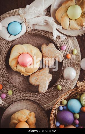 Easter wreaths made from yeast dough for Easter brunch with colored eggs and pastries, vertical Stock Photo