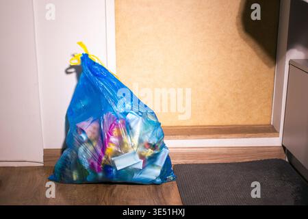 Blue plastic bag for trash waste near home entry door ready to be thrown away. High quality Stock Photo