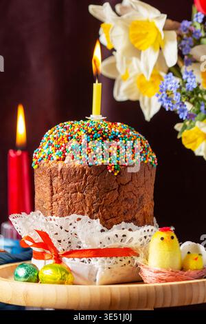 Easter composition with kulich, painted eggs, bouquet of daffodils and tulips, and candles Stock Photo