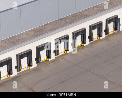 Aerial view shows a logistics center with multiple warehouse buildings and loading docks in operation for freight movement. Stock Photo