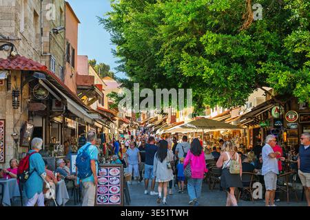 The effects of over tourism caused by too many ships in port as visitors crowd the narrow shopping streets of old town medieval Rhodes, Greece. Stock Photo