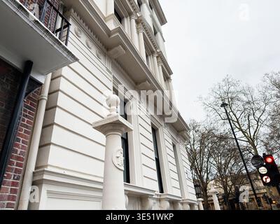 Elegant white stucco townhouse with classical columns and ornamental pillar on a London, UK street. Stock Photo