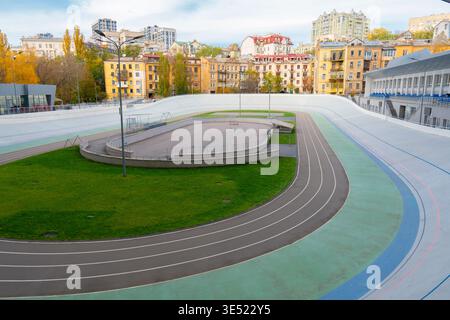 Urban cycling track and sports complex in a city district with residential buildings. Empty velodrome with running paths on a bright autumn day Stock Photo
