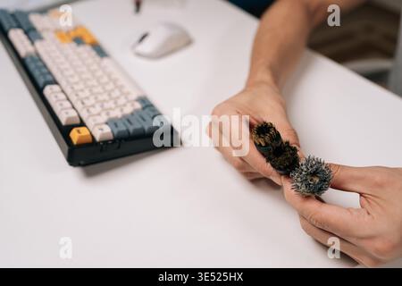Three steam-cleaner brushes held over white desk with keyboard and mouse, one worn and dirty, other new and pristine, highlighting hygiene Stock Photo