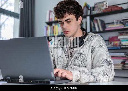 High school student preparing for exams using laptop and books. Teenager studying at desk with laptop, modern education concept Stock Photo