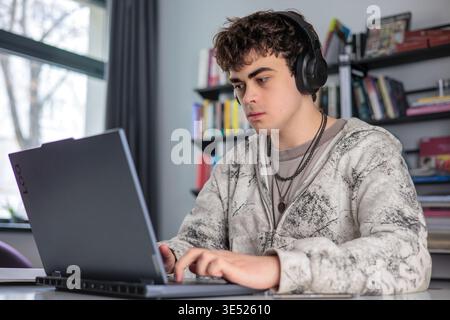 High school student preparing for exams using laptop and books. Teenager studying at desk with laptop, modern education concept Stock Photo