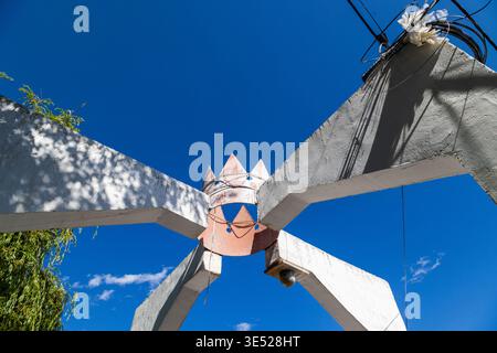 Abstract sculpture shaped like a crown stands against a clear blue sky. Stark architectural lines and slightly weathered texture create a striking visual. Stock Photo