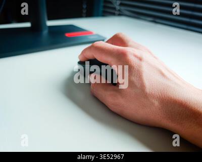 Hand of working person holding computer mouse on desk, office workspace detail with modern technology and everyday productivity concept. Work concept Stock Photo