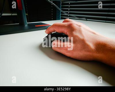 Hand of working person holding computer mouse on desk, office workspace detail with modern technology and everyday productivity concept. Work concept Stock Photo