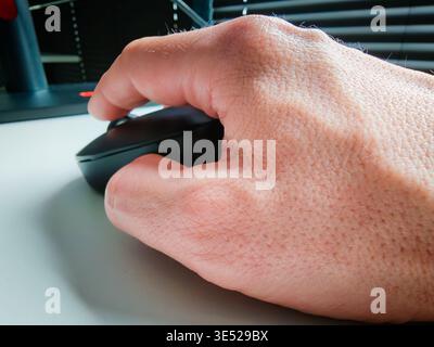 Hand of working person holding computer mouse on desk, office workspace detail with modern technology and everyday productivity concept. Work concept Stock Photo