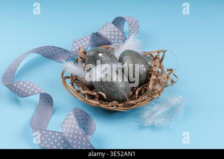Easter holiday composition eggs nest feathers and ribbon Stock Photo