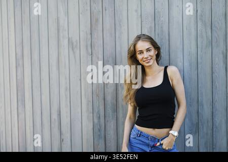 Young beautiful woman posing at wall, standing outdoors Stock Photo