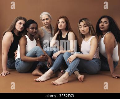 Diverse women in casuals sitting on brown background. Multi-ethnic group of females looking at camera in studio Stock Photo