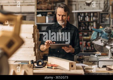 Senior carpenter using a digital tablet in his workshop Stock Photo