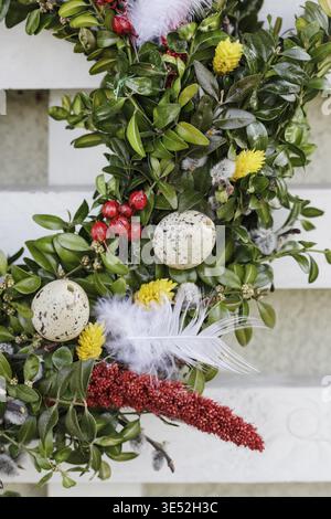 A charming Easter wreath for the door or wall, handmade with flowers, eggs and feathers. Festive decor Stock Photo