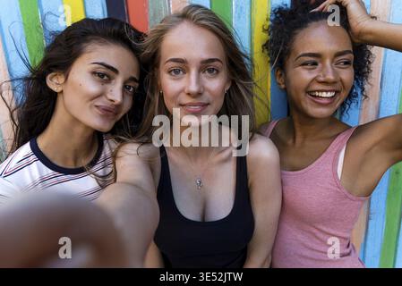Group of young friends posing while taking selfie. Three smiling women having fun Stock Photo