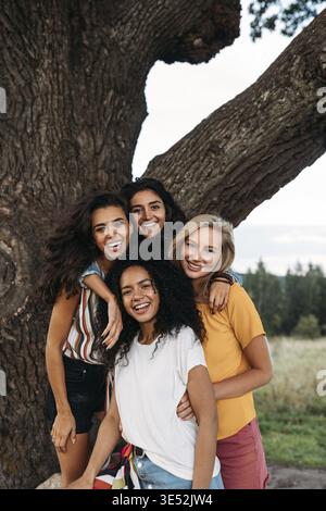 Group of young diverse women standing in front of a big tree Stock Photo