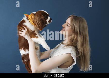 Side view of young woman holding her little dog in studio Stock Photo