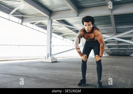 Muscular runner with eyes closed taking deep breath during intense training Stock Photo