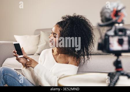 Female vlogger using smartphone while recording a video Stock Photo