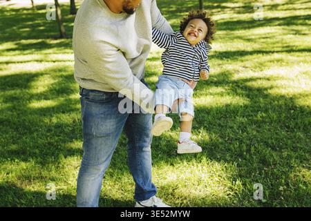 Man holding his son on hands outside. Happy kid looking on father Stock Photo
