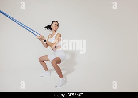 Young slim woman doing sit-ups and using a resistance band Stock Photo
