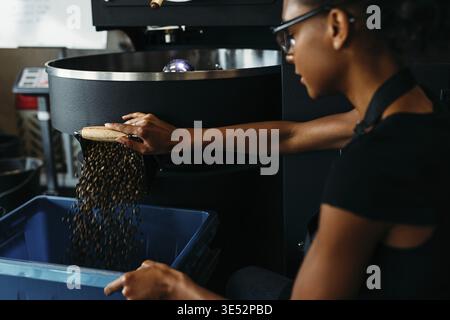 Female barista using industrial coffee roasting machine in cafe Stock Photo