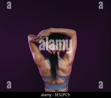Back view of a young athlete stretching her arms before workout Stock Photo