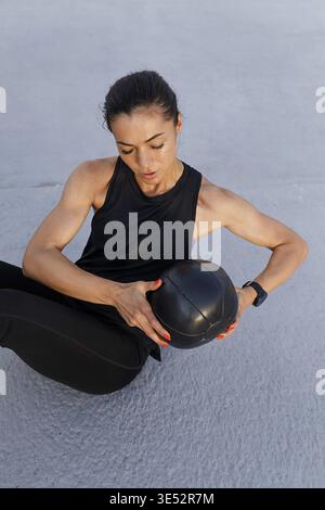 High-angle view of young, muscular female athlete doing core exercises with a medicine ball Stock Photo