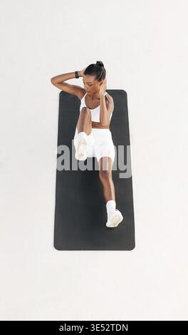 High angle of a fit woman doing abs exercises. Full length of a young female on a mat outdoors Stock Photo