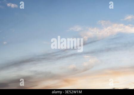 Sky at sunset with a gradient of color from warm to cold. Sky background with light stretched clouds in the sun Stock Photo