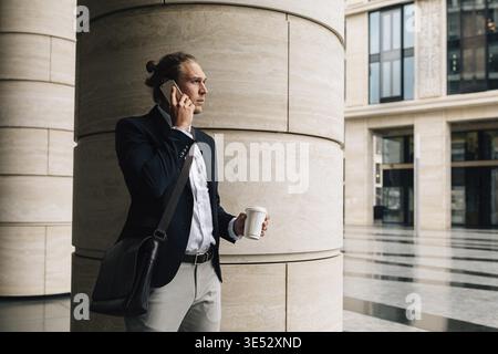 Stylish man talking on cell phone holding coffee Stock Photo