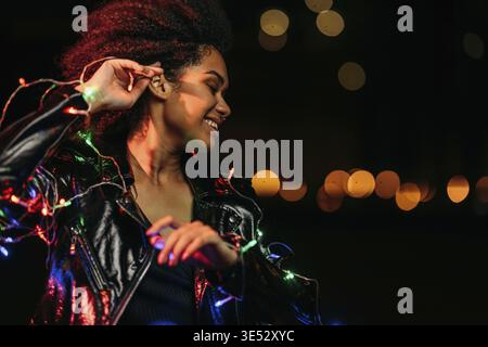 Side view of young woman posing at night in front of a city lights outdoors Stock Photo