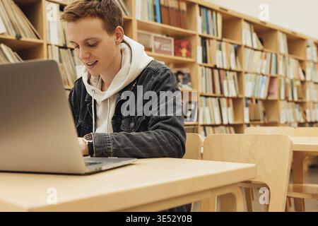 Smiling student preparing for exams in college library Stock Photo