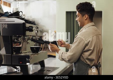 Side view of a barista using a coffee machine. Coffee shop owner preparing coffee Stock Photo