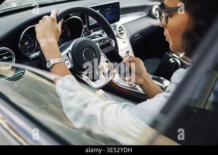Unrecognizable woman using smartphone while sitting in car Stock Photo