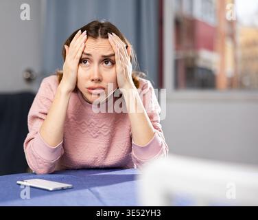 Portrait of a frustrated young woman sitting at a table Stock Photo