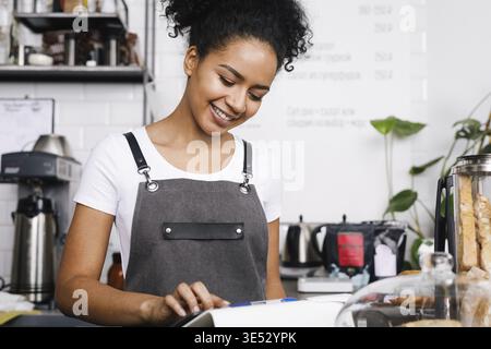 Smiling beautiful waitress using digital tablet in cafe Stock Photo