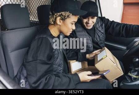 Two couriers sitting in van checking information on box for delivery Stock Photo