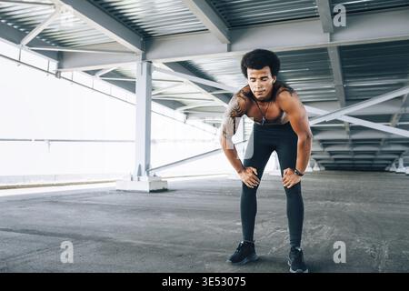 Muscular runner with eyes closed taking deep breath during intense training Stock Photo