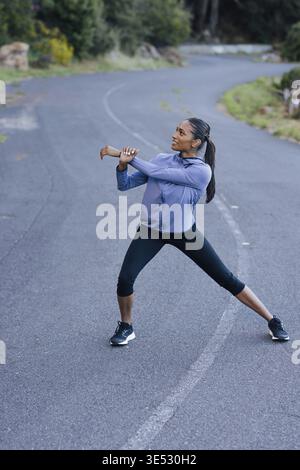 Young slim female warming up her body on an abandoned empty road Stock Photo