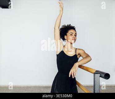 Professional ballet dancer practicing at barre in small studio Stock Photo