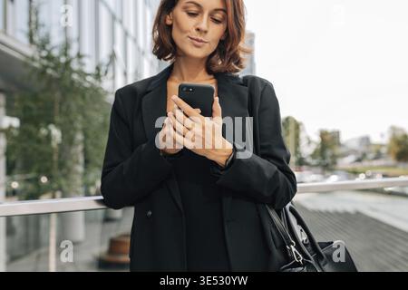 Close-up of a middle-aged businesswoman in formal clothes using a mobile phone Stock Photo