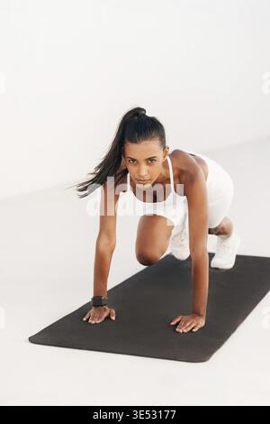 Woman doing core exercises on a mat and looking at camera Stock Photo