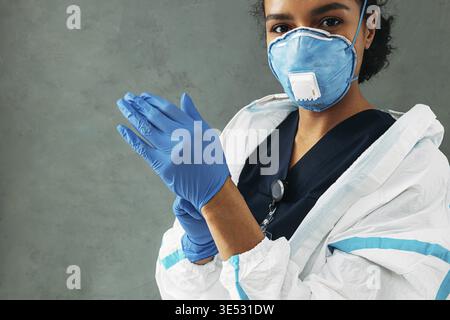 Young medical worker puts on surgical gloves looking at camera Stock Photo